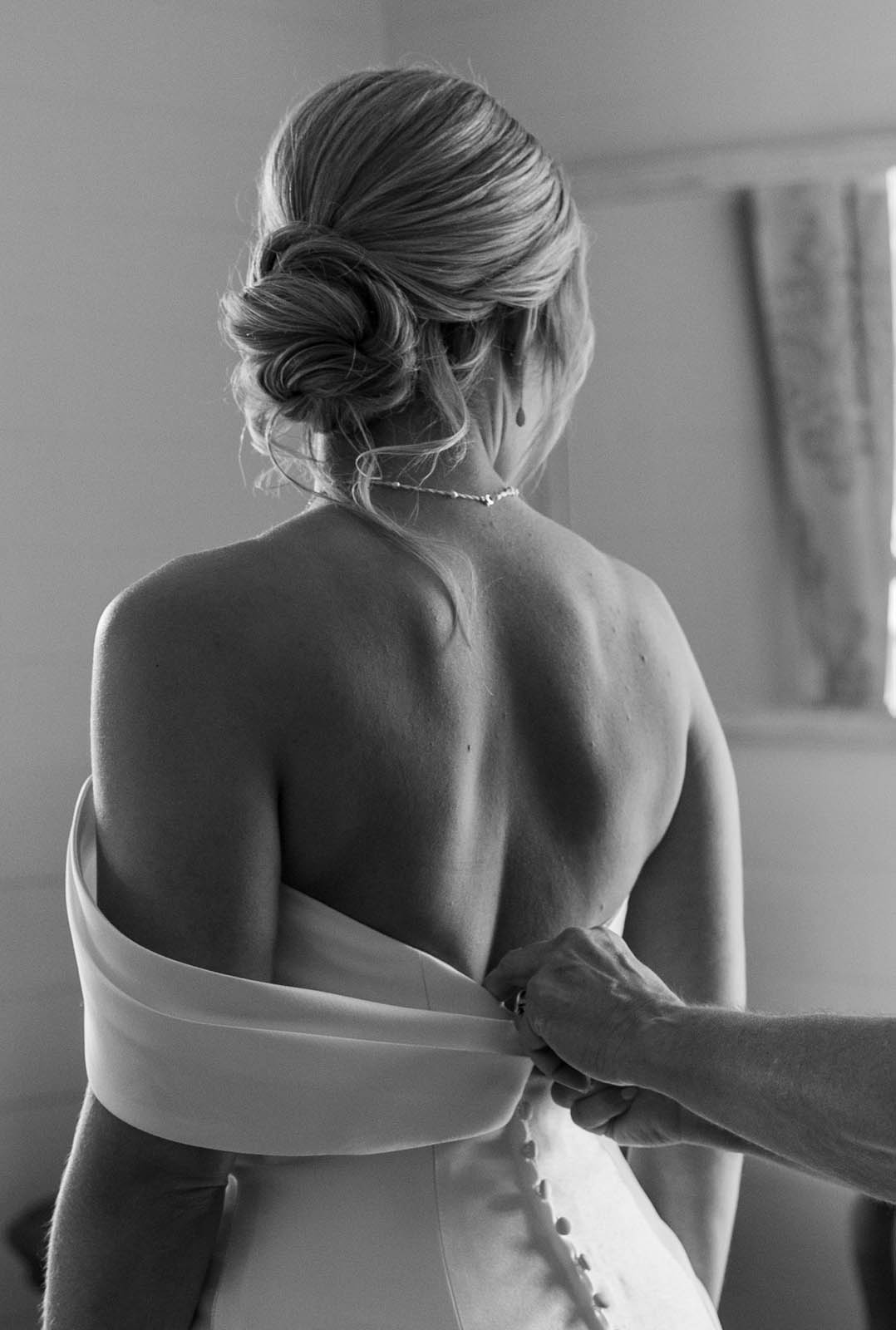 Bride being buttoned up by her mother on her wedding day