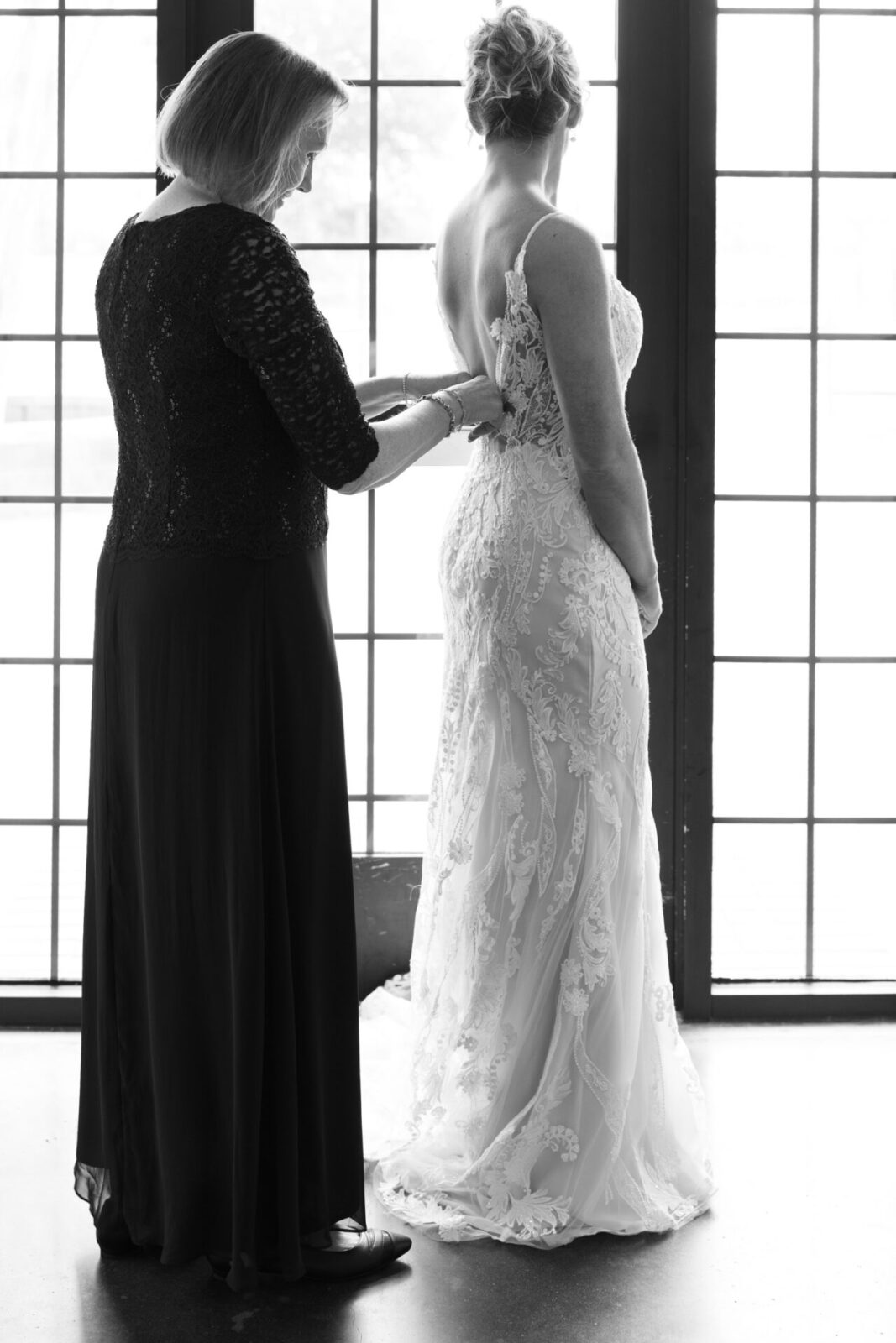 Mother zipping up a bride in her wedding dress