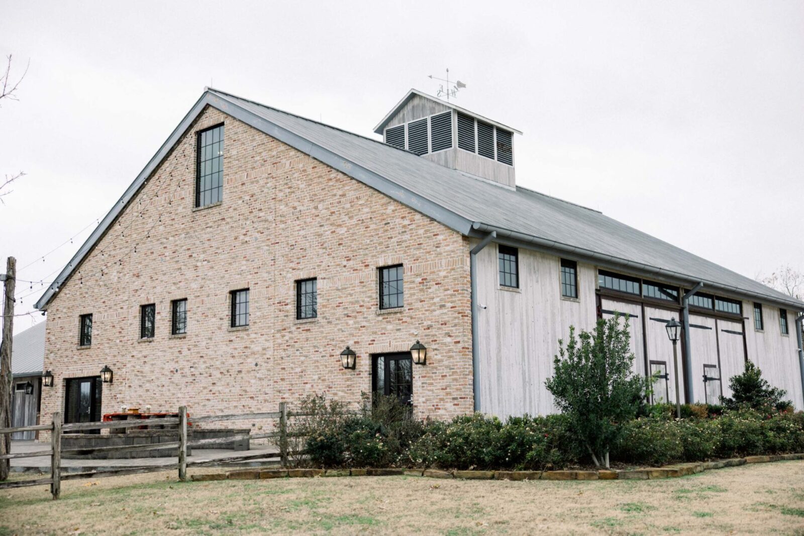 A large red brick and white wood barn.