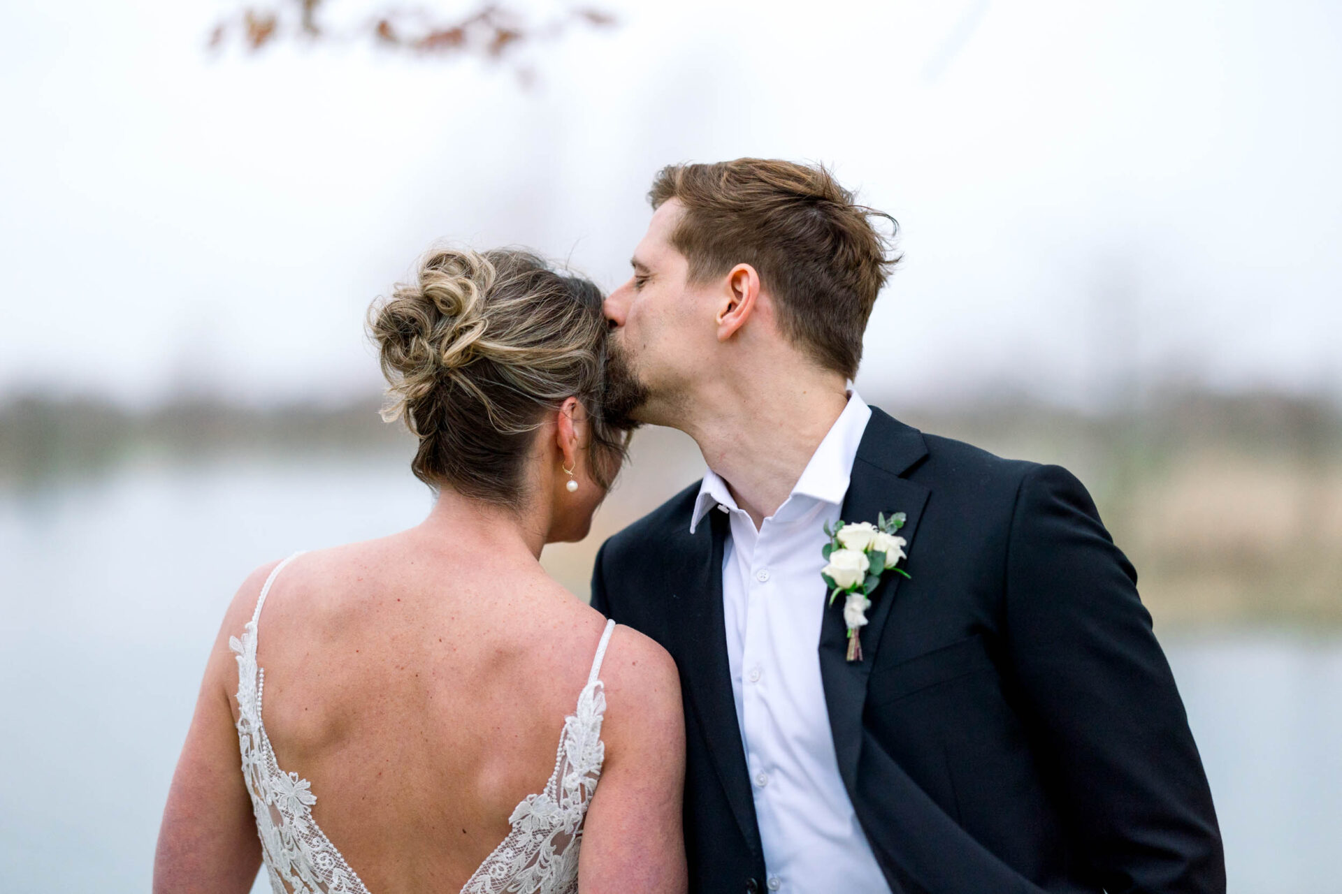 Groom kissing brides temple on a wedding day.