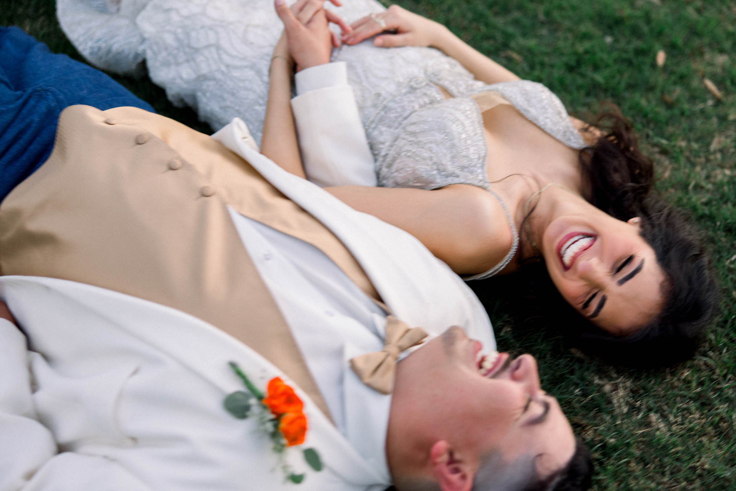 A bride and groom laughing on the ground